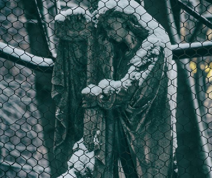 A stone statue behind a wire fence