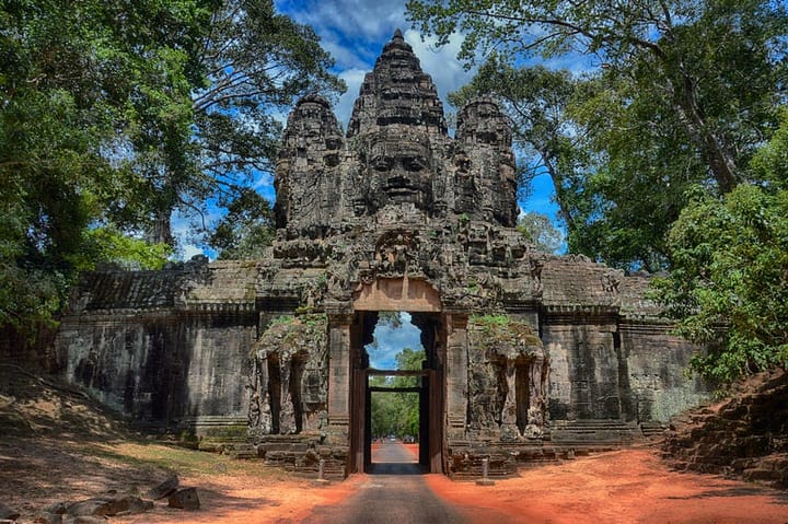 A temple at the Angkor Wat complex in Cambodia, with blue sky behind and green foliage to either side.