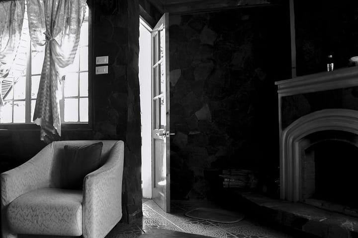 Black and white photo of a room’s interior with a door ajar